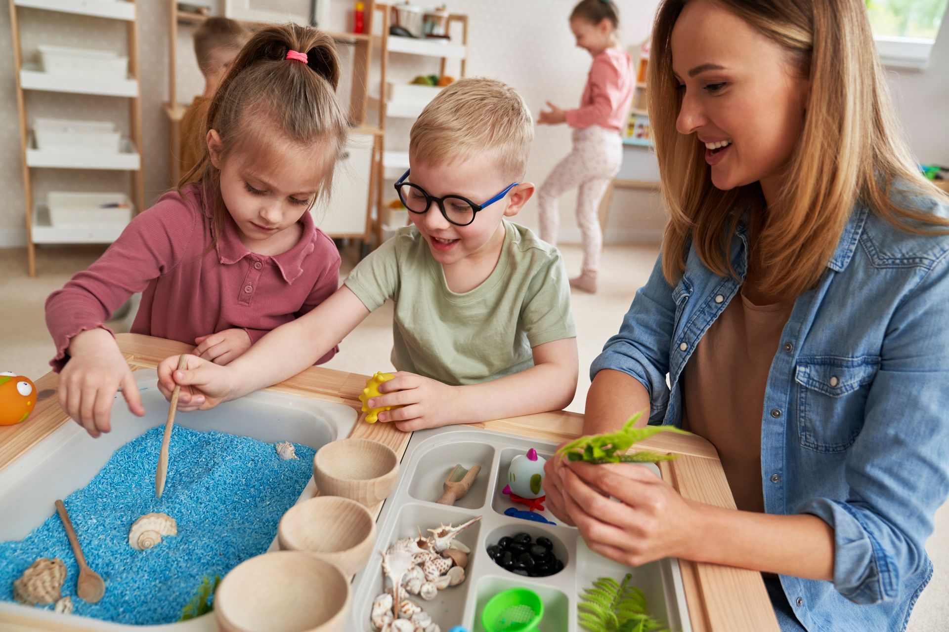 A teacher playing with preschool children in a classroom. A teacher playing with preschool children in a classroom.