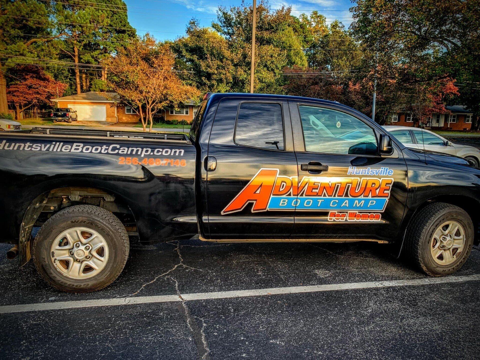A black truck with the word adventure on the side is parked in a parking lot.