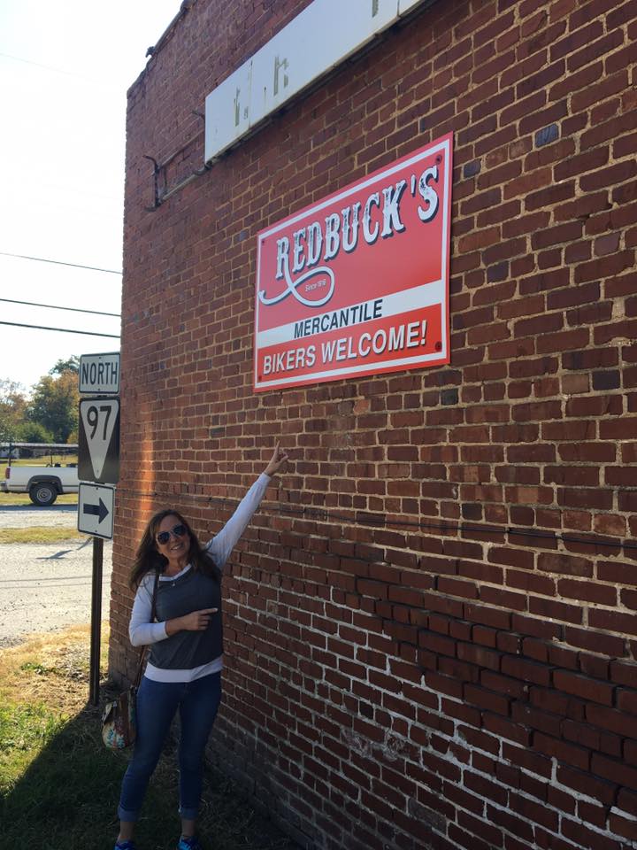 A woman stands in front of a redbuck 's sign