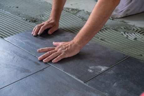A person is laying tiles on the floor.