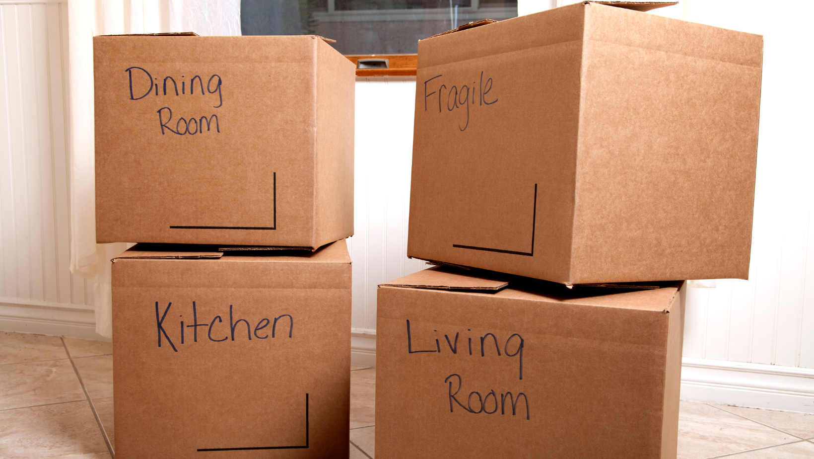 Four cardboard boxes are stacked on top of each other labeled dining room kitchen and living room
