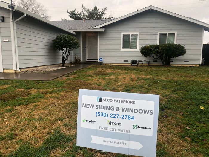 a house with a sign in front of it that says `` new siding & windows '' .
