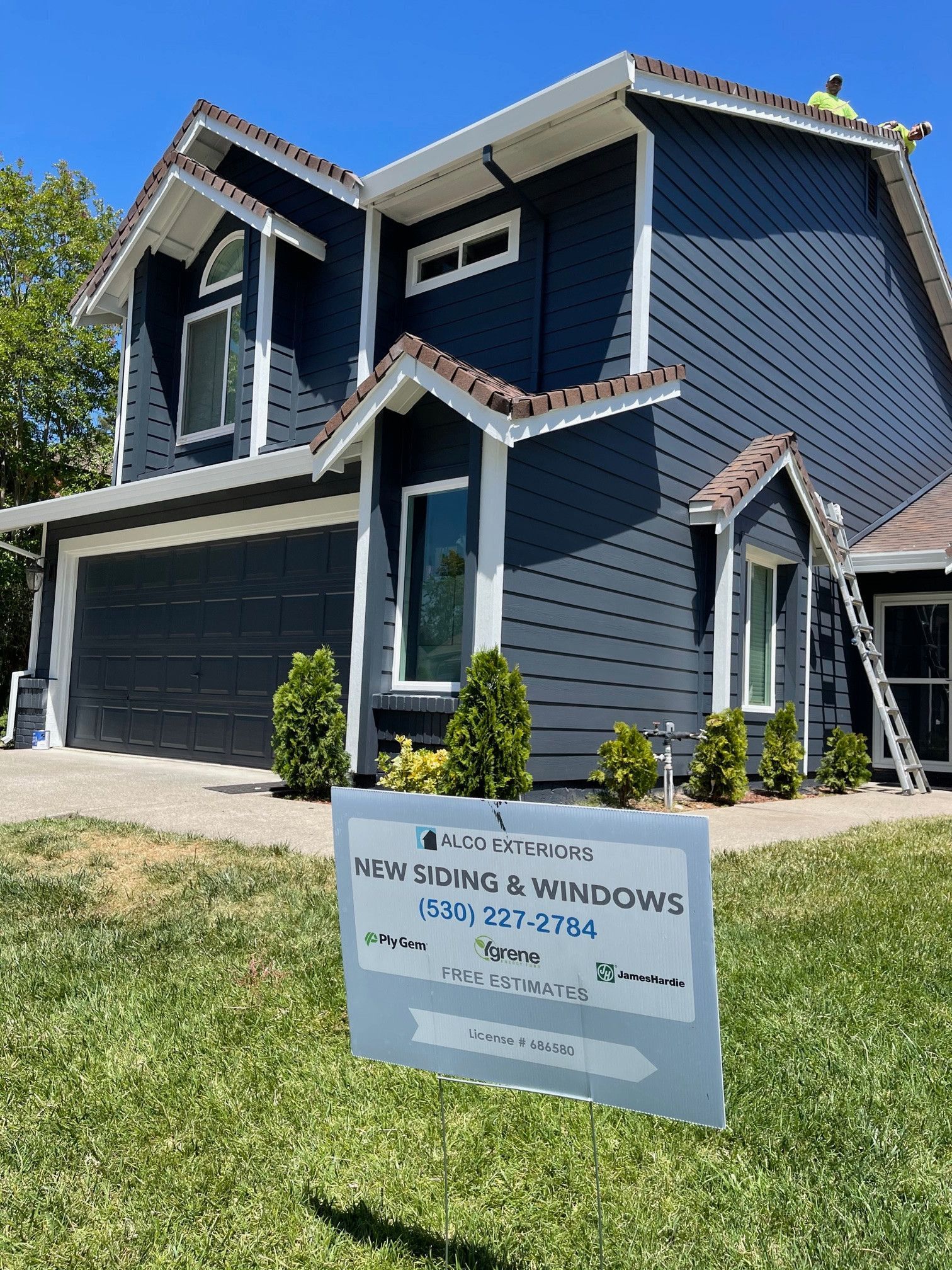 Blue house with white trim, new siding sign in front.