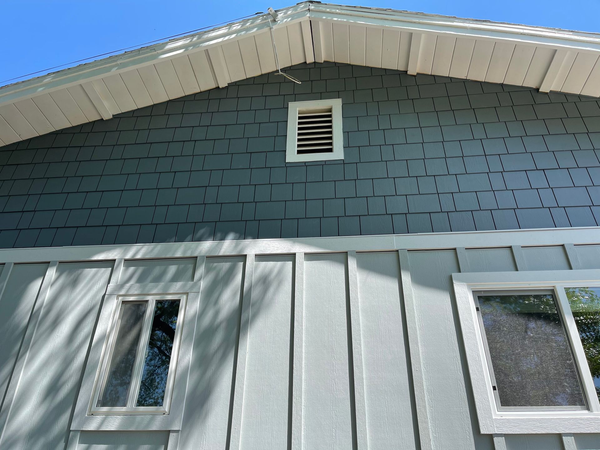 a gray house with a white roof and a window