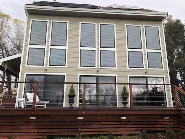 the back of a house with a large deck and lots of windows.