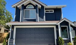a blue house with a white trim and a garage door.