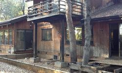 a large wooden house with a balcony and trees in front of it.
