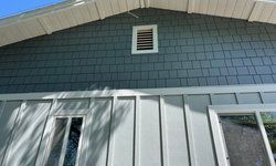 a close up of a house with a gray siding and a white roof.