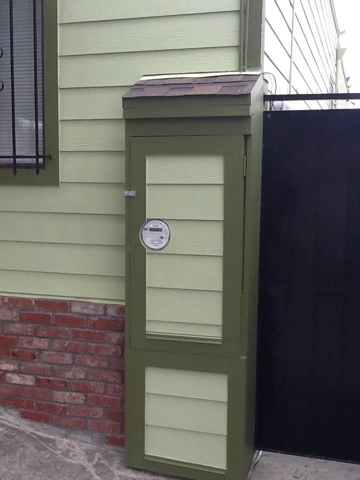 a green box with a thermometer on it is outside of a house .