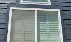 a window with shutters on it is on the side of a house.
