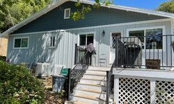 a small house with a deck and stairs leading up to it.