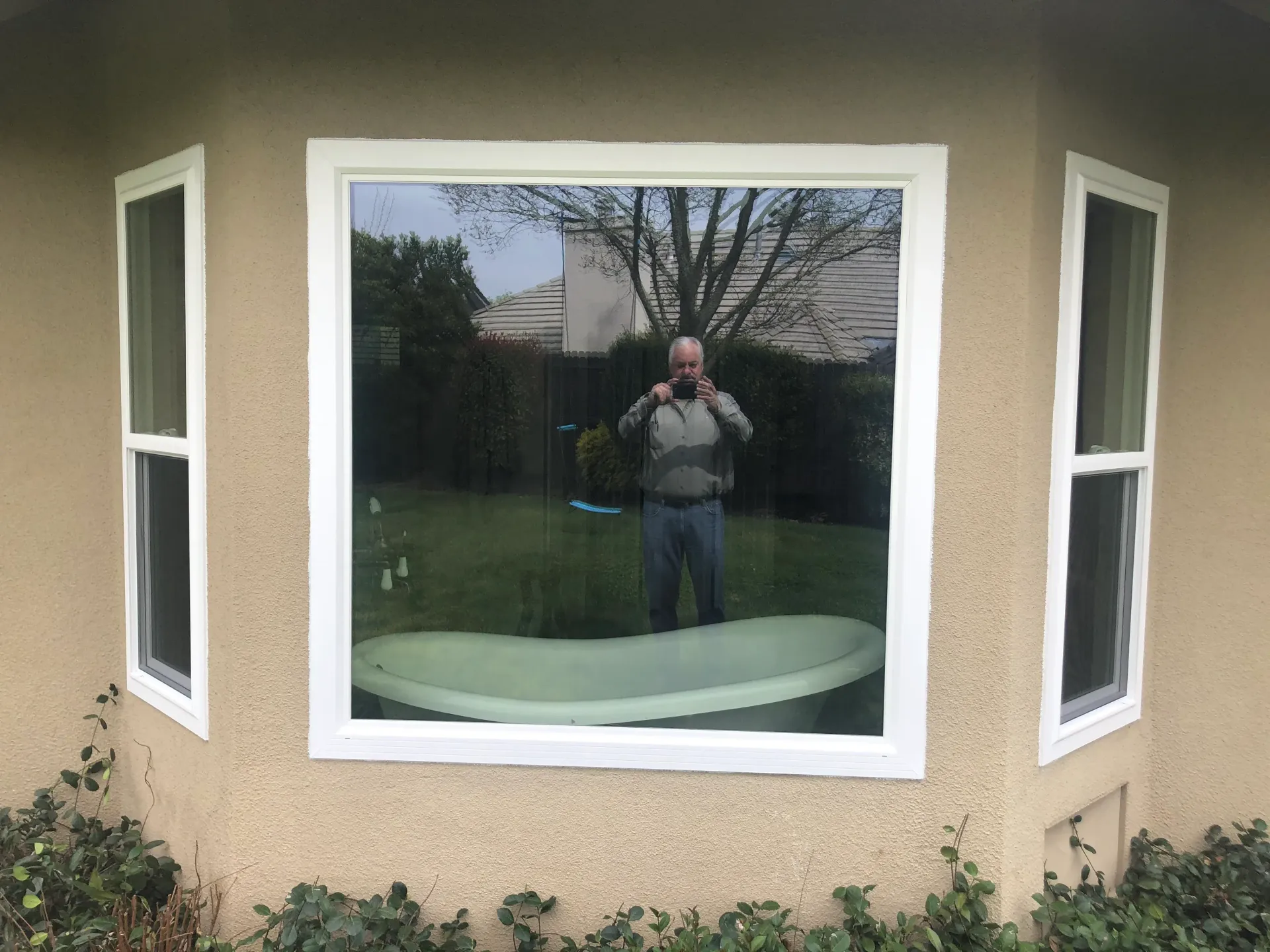 a man is taking a picture of himself in a bay window.