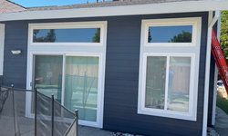 a small house with a sliding glass door and two windows.