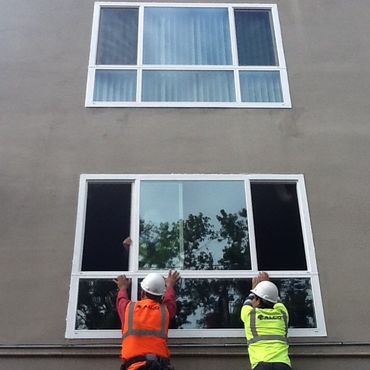 two men wearing hard hats are working on a window