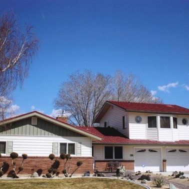 a white house with a red roof and a blue sky in the background.