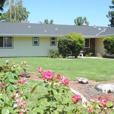 a house with a lush green lawn and flowers in front of it