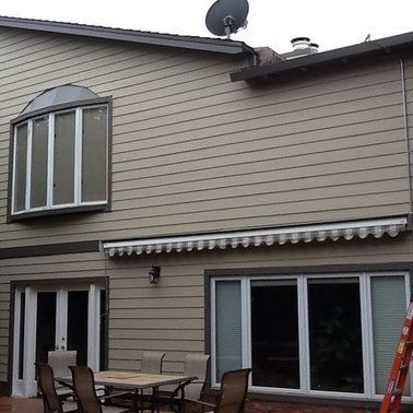 the back of a house with a table and chairs and a satellite dish on the roof.