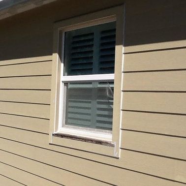 a window on the side of a house with shutters on it .