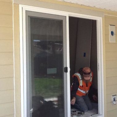a man is kneeling down in front of a sliding glass door.