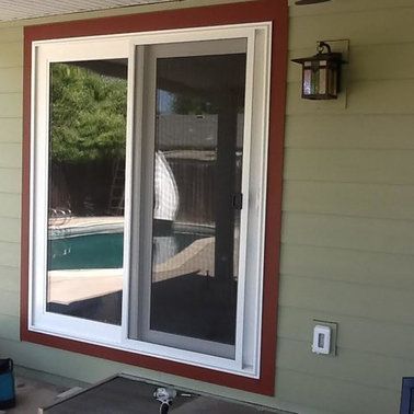 a sliding glass door with a screen on it is on a patio next to a pool .