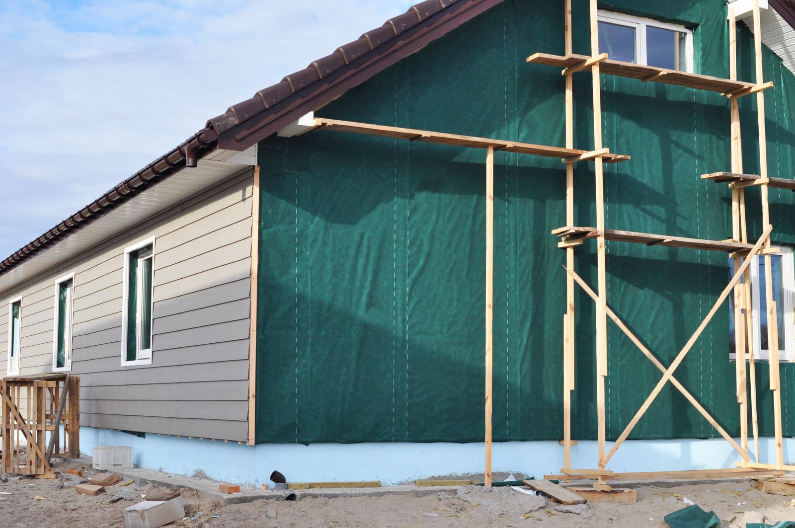 A house is being remodeled with green siding and scaffolding