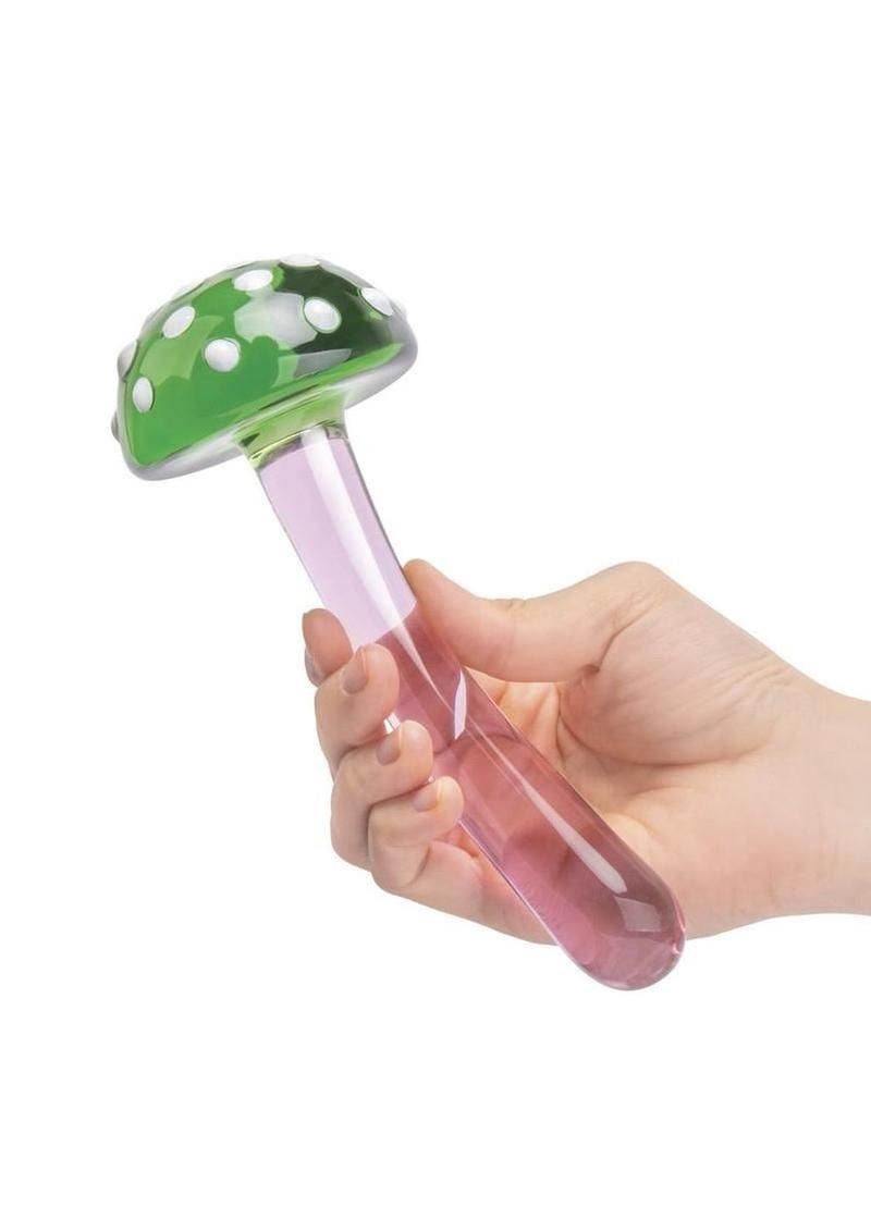 Hand holding a pink and green mushroom-shaped glass toy.