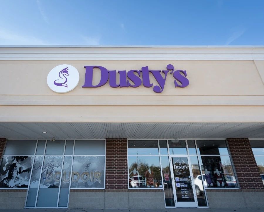 The front of a dusty 's store with a purple sign