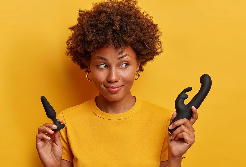 A woman in a yellow shirt is holding two toys in her hands.