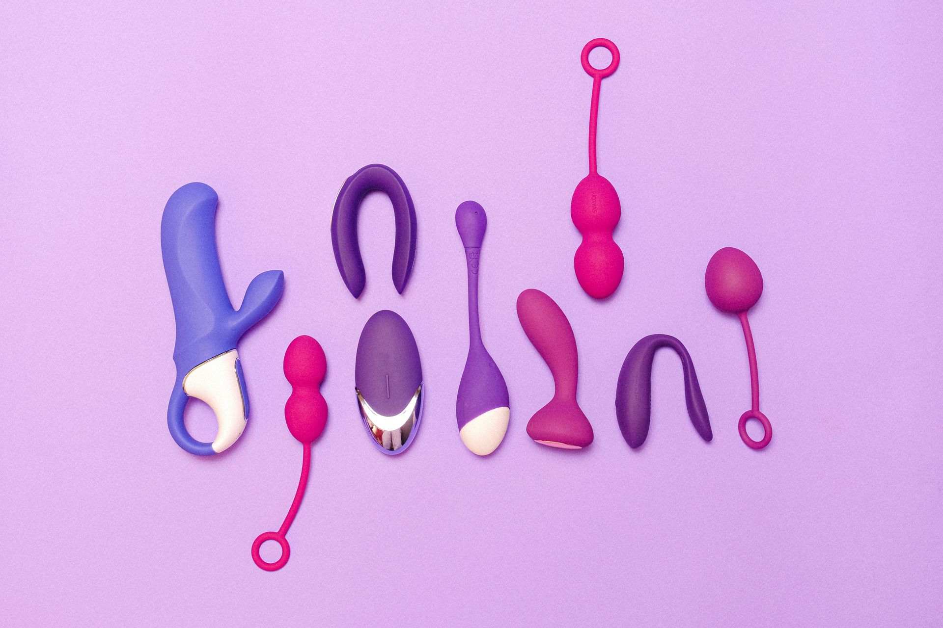 Various colorful sex toys arranged on a purple background.