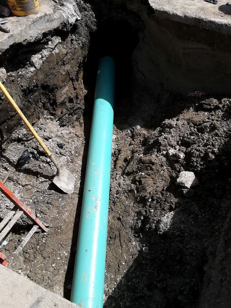 Sewer line repair in progress with exposed pipe and trench excavation

