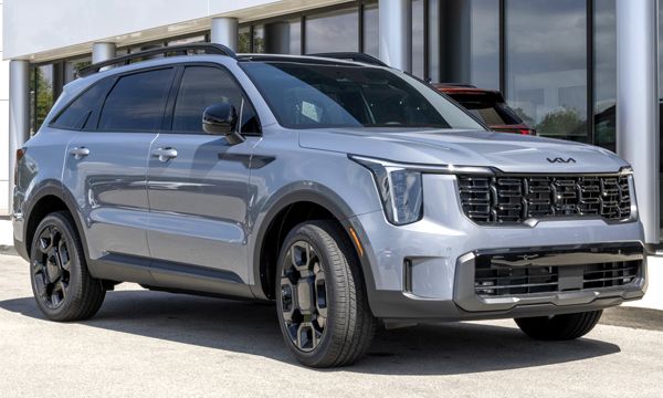 Gray Kia Telluride SUV parked in front of a building, with black wheels and roof rails.