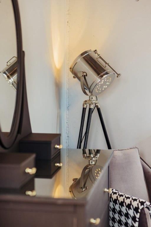 Auf einem Tisch steht neben einem Spiegel eine Lampe.