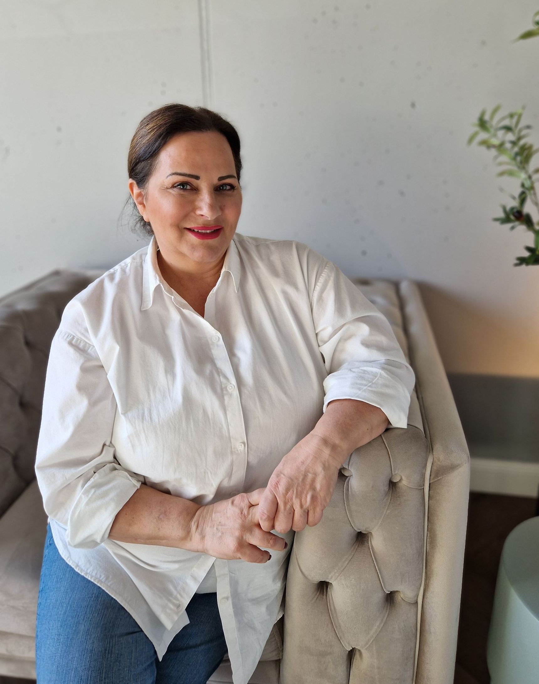 Eine Frau in einem weißen Hemd sitzt auf einem Sofa.