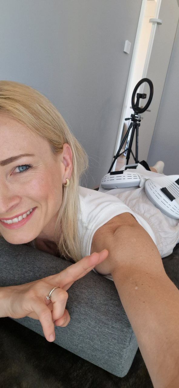 Eine Frau liegt auf einem Sofa und zeigt auf ihren Arm.