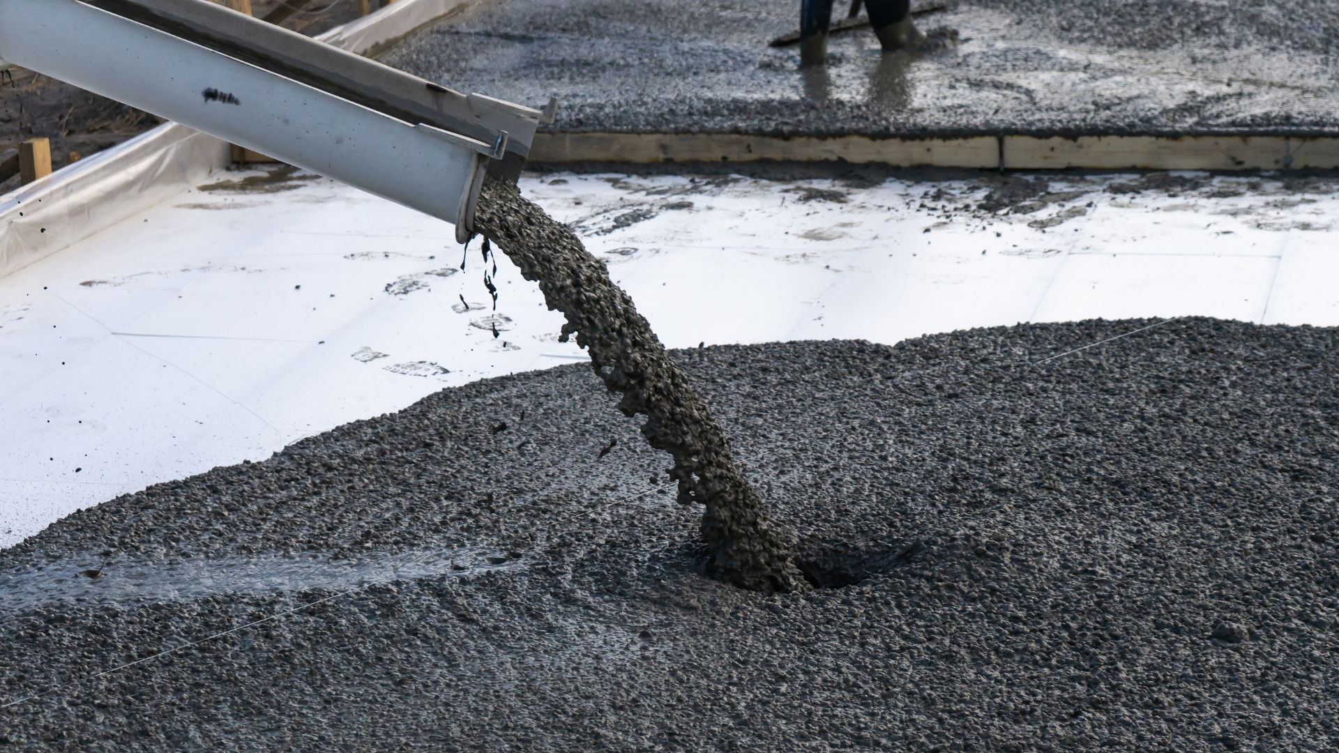 A person is pouring concrete into a pile of gravel.
