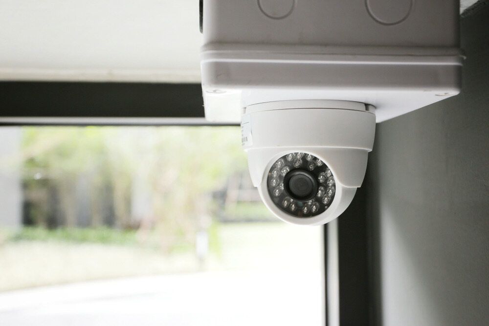 A Security Camera Is Hanging From The Ceiling Next To A Window — Fortress Locksmiths & Security in Hornsby, NSW