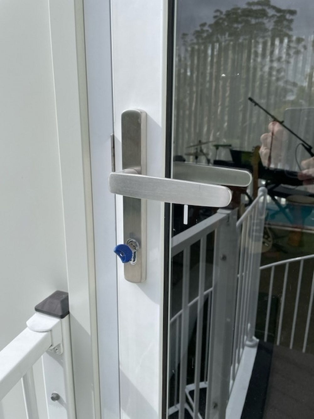 A White Door With A Silver Handle And A Blue Key On It — Fortress Locksmiths & Security in West Pennant Hills, NSW