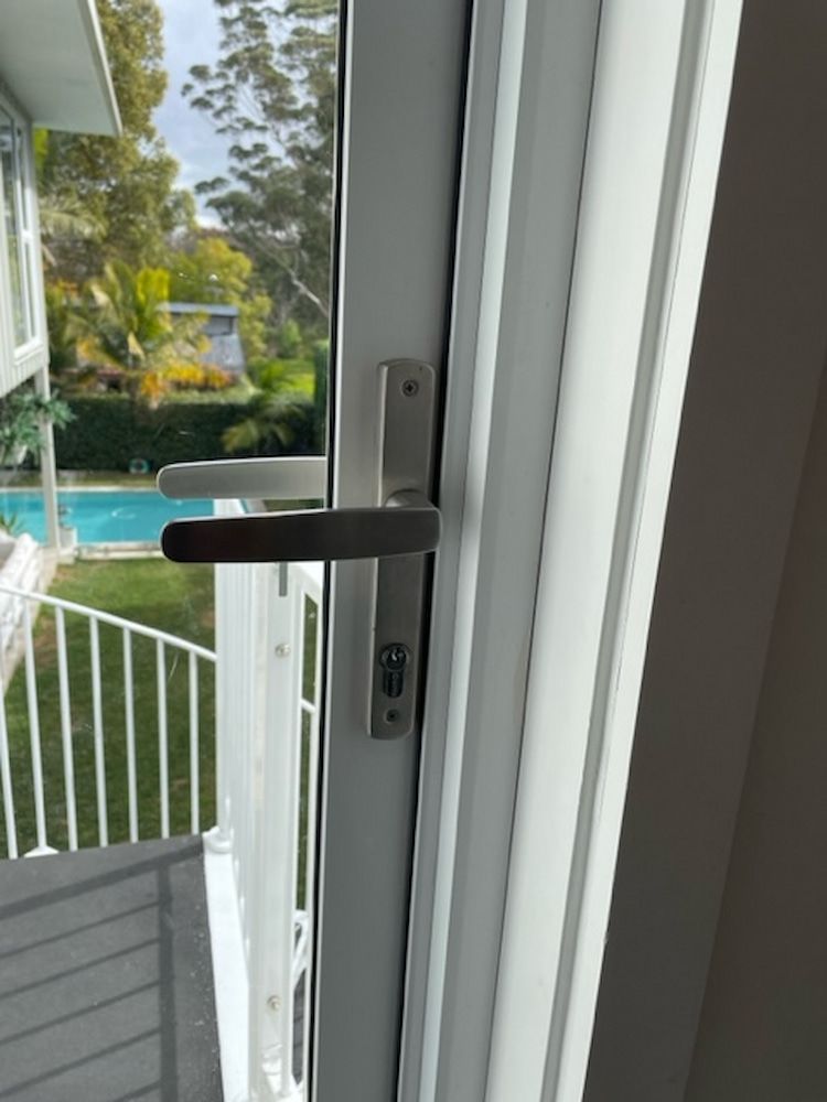 A Door Handle On A Window With A Pool In The Background — Fortress Locksmiths & Security in North Ryde, NSW