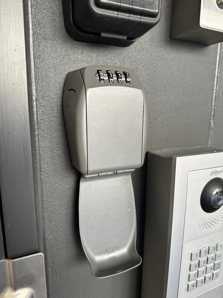A Key Box Is Sitting On A Wall Next To A Keypad — Fortress Locksmiths & Security in Castle Hill, NSW