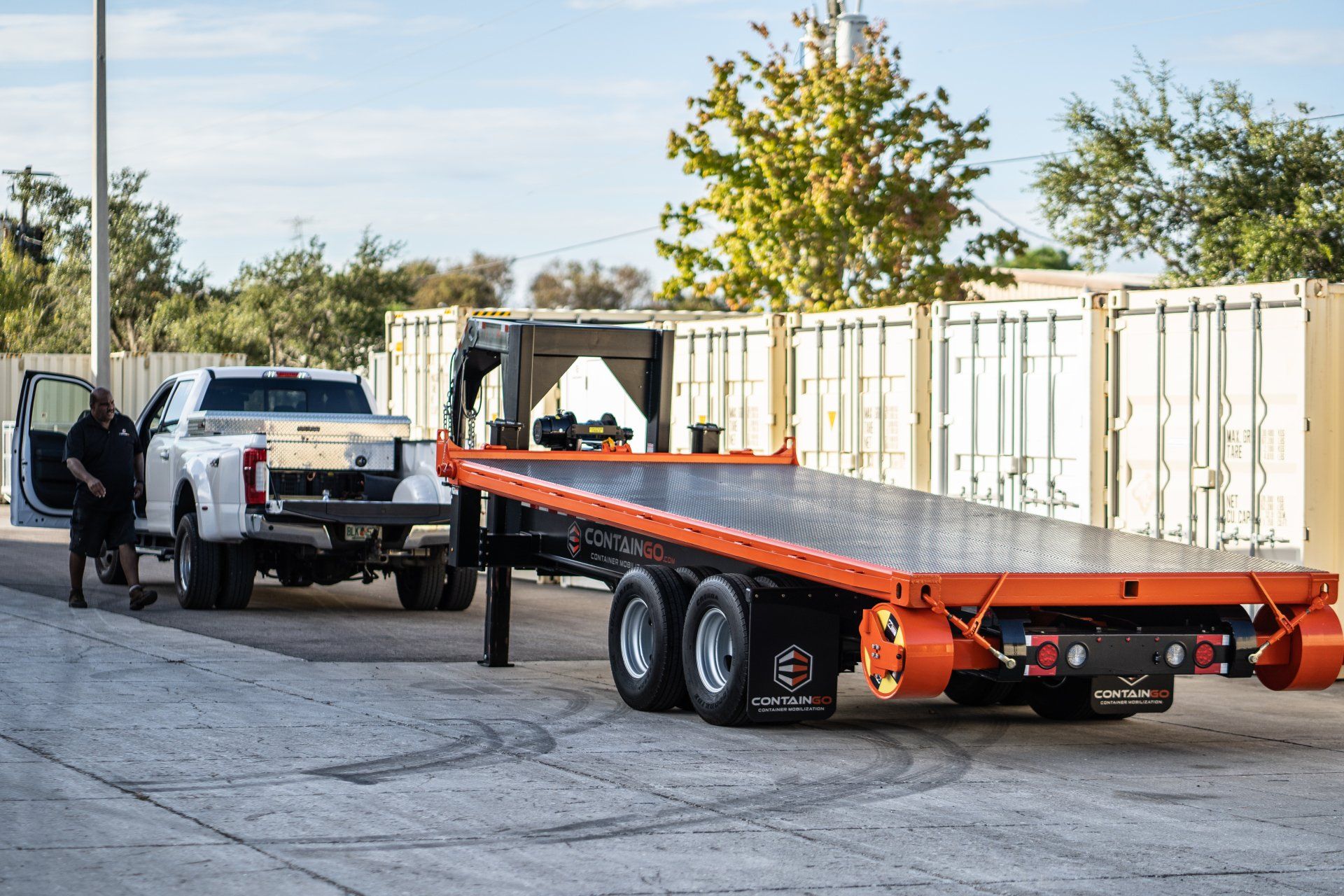 a man is standing next to a tow truck with a flatbed trailer attached to it .
