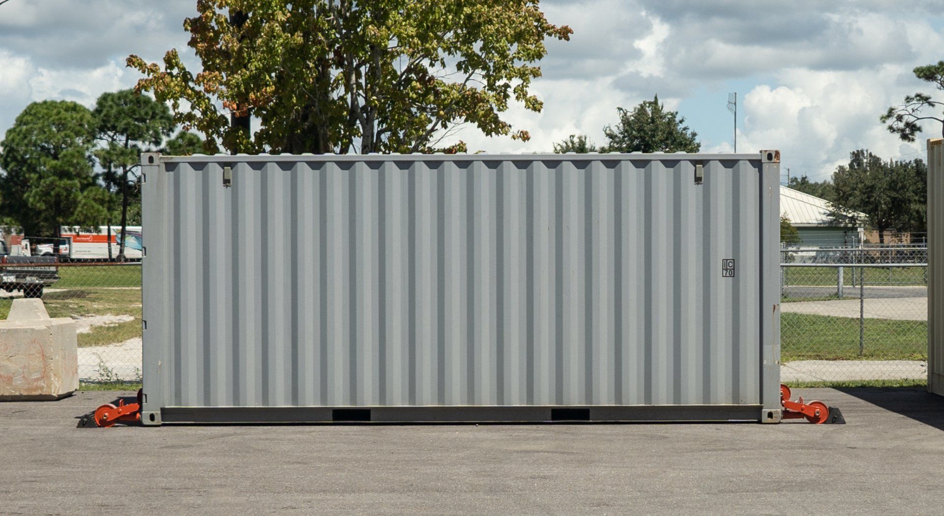 a gray shipping container is sitting in a parking lot with two sets of ContainGo container end wheels attached