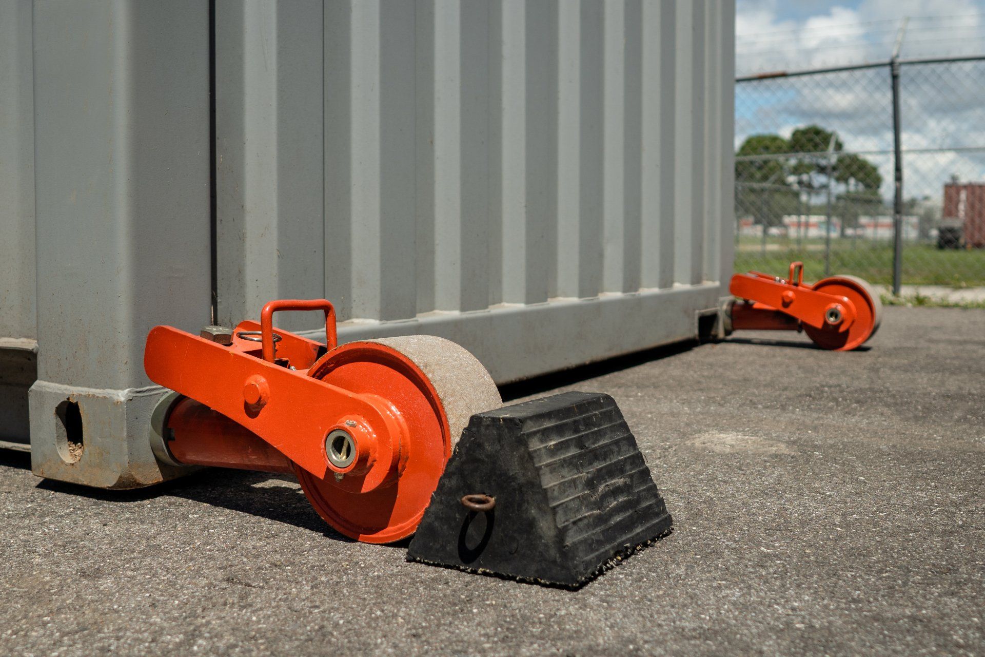 a gray shipping container is sitting in a parking lot with two sets of ContainGo container end wheels attached