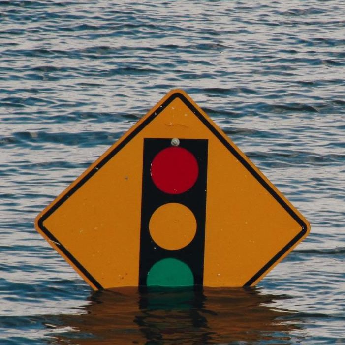 a yellow sign with a traffic light on it is floating in the water