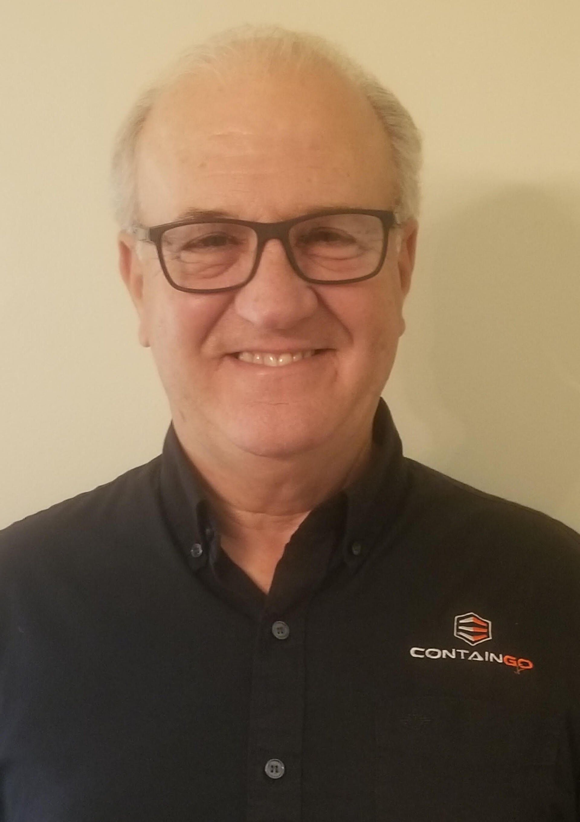 a man wearing glasses and a black shirt is smiling for the camera .