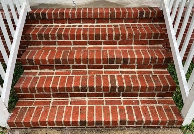 Brick steps leading up to a building, with white railings on either side.