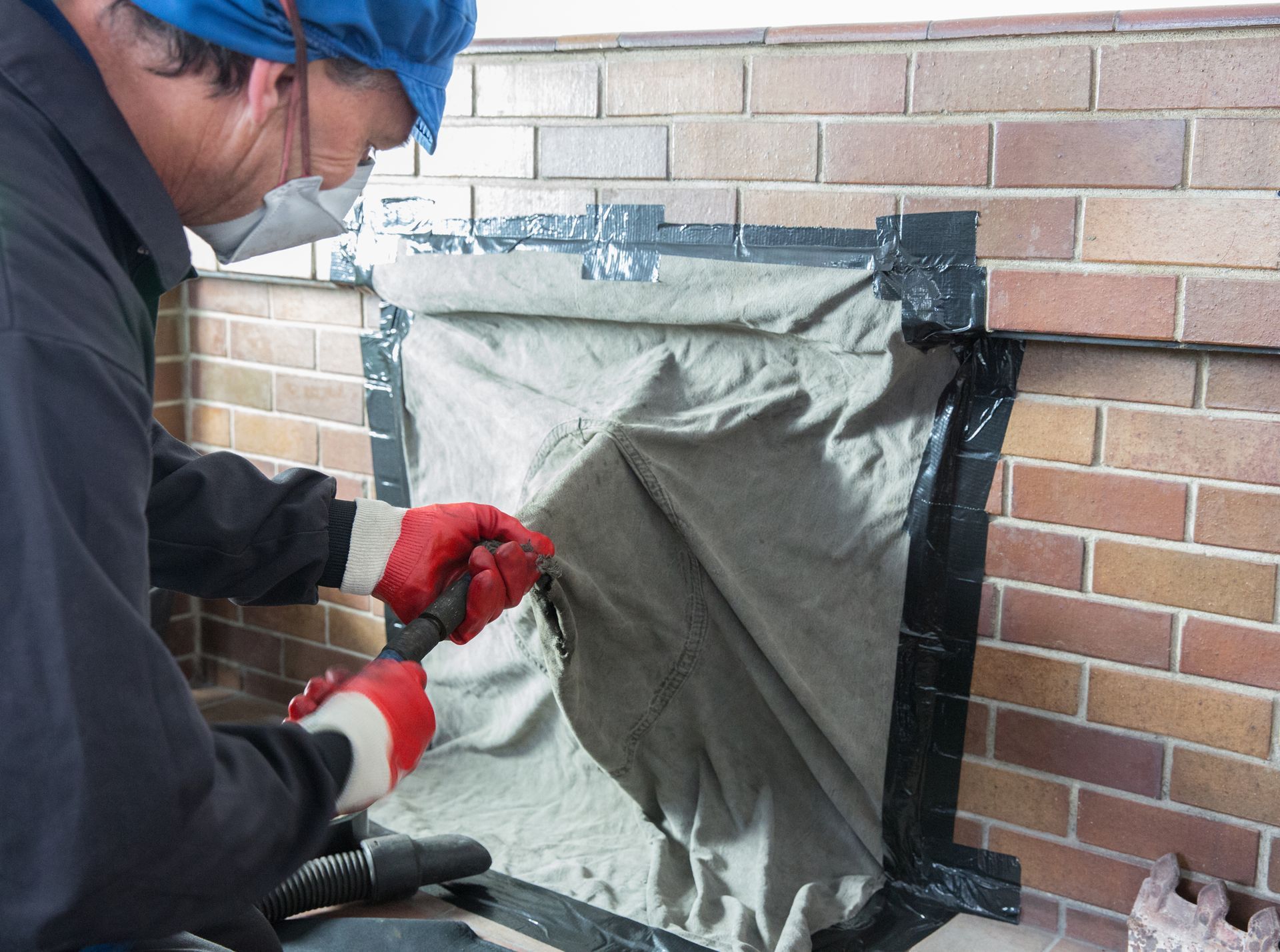 A person wearing a mask and gloves painting a brick wall | Chimney Cleaning in Virginia Beach VA