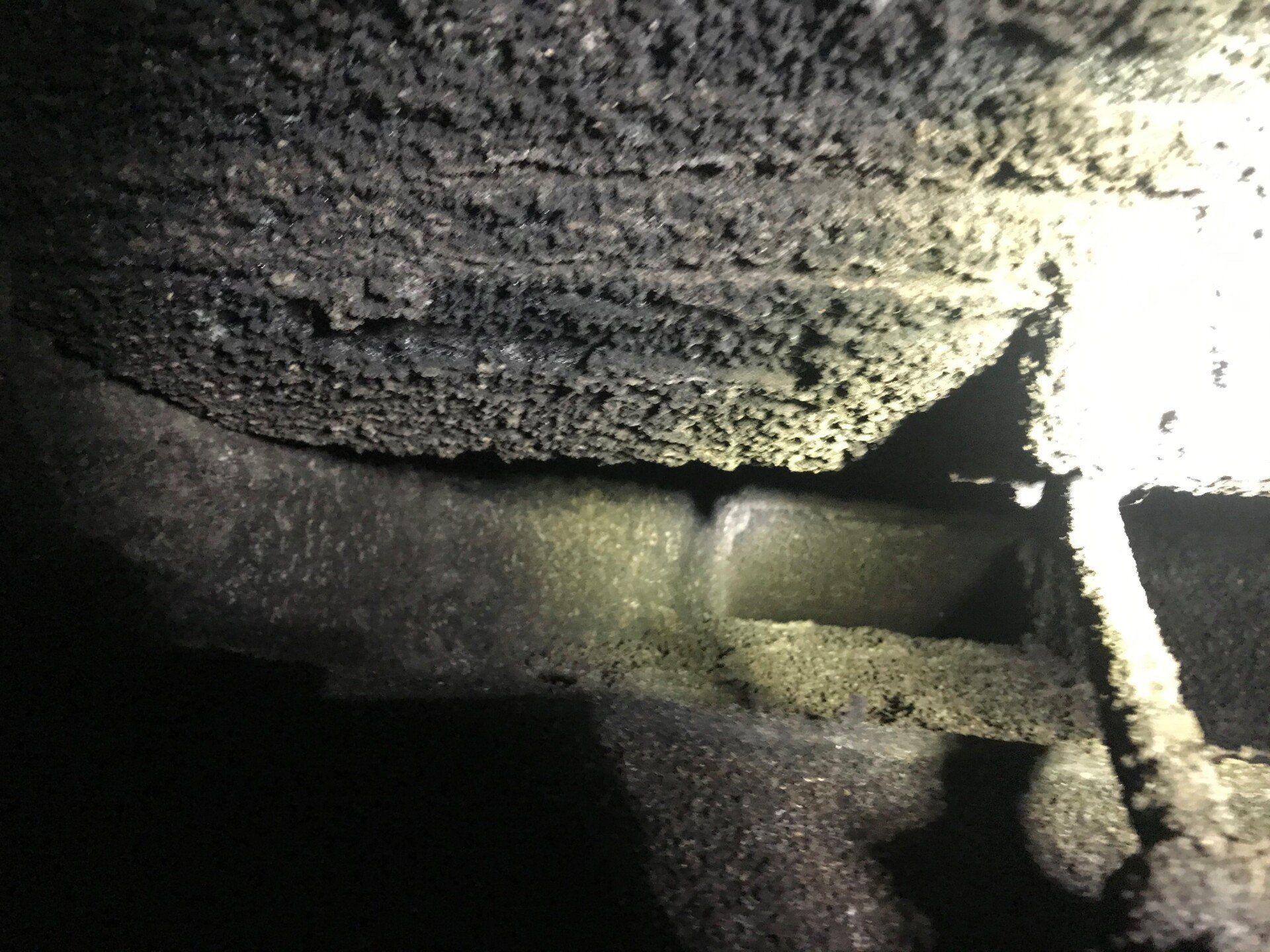 Inside of a dark chimney, showing thick layers of black creosote buildup.