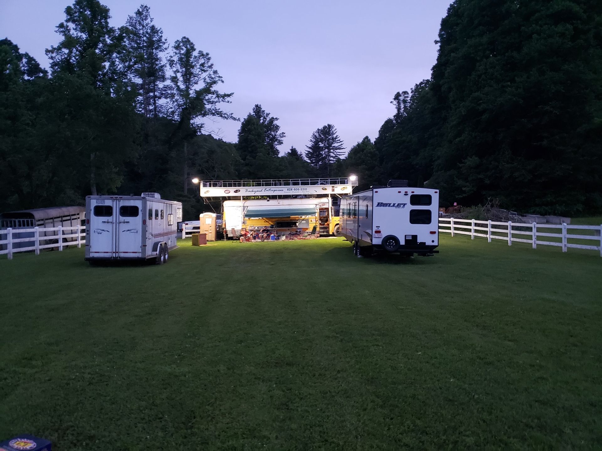 Two horse trailers are parked in a grassy field