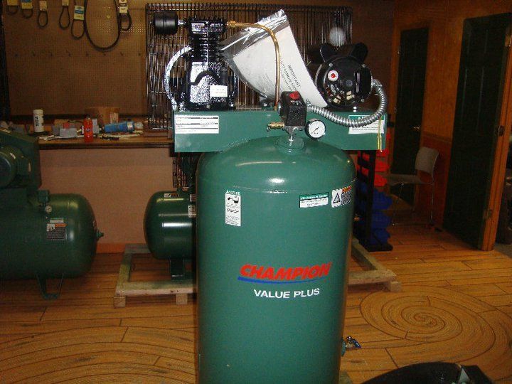 A champion value plus air compressor is sitting on a wooden floor