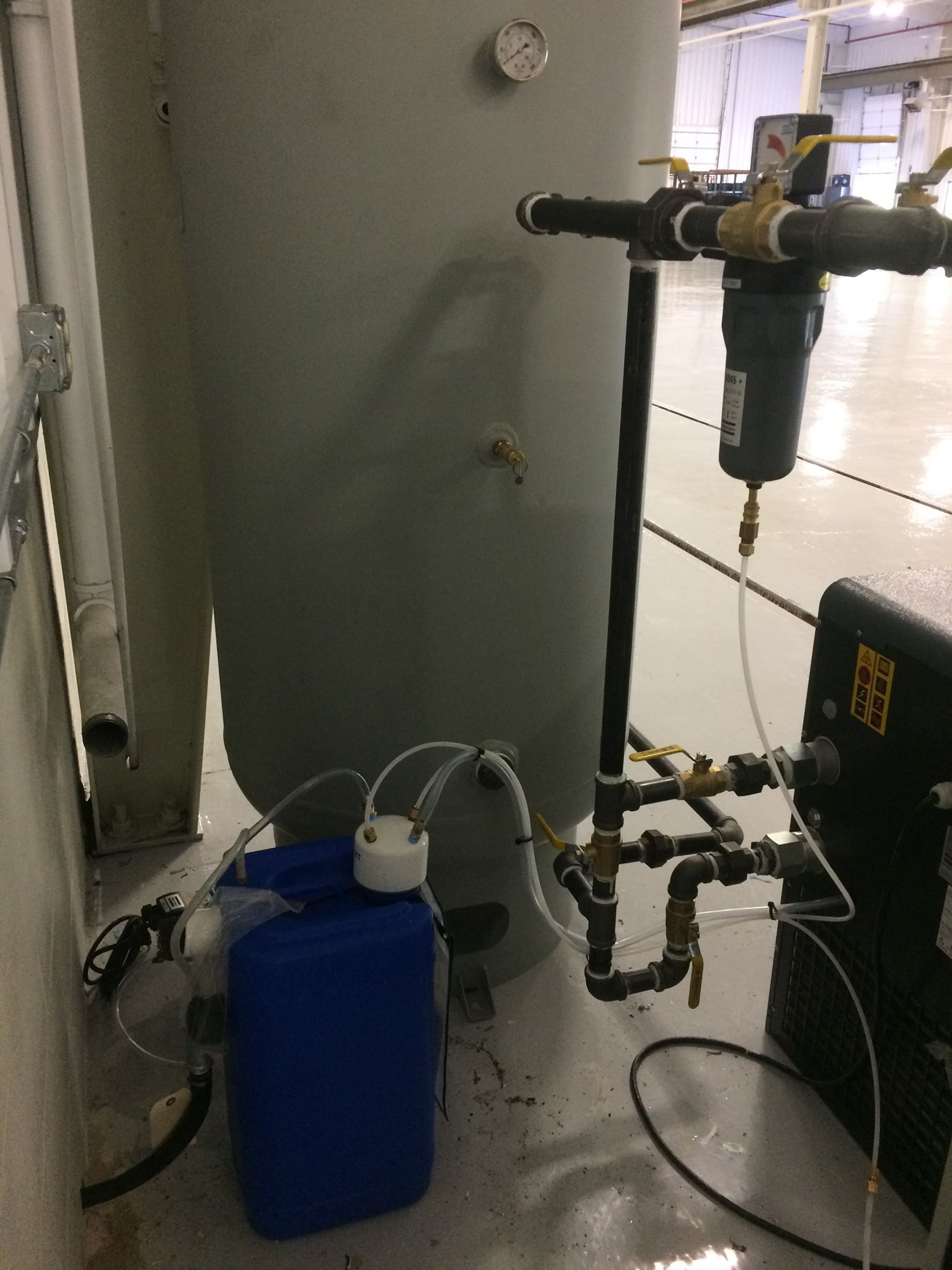 A blue container is sitting next to a large metal tank.